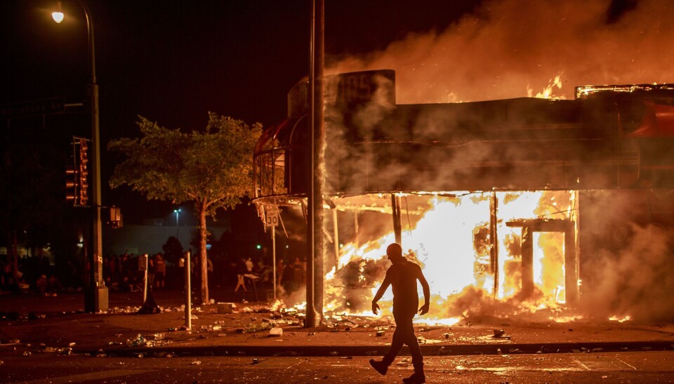 En mann går forbi et alkooholutsalg i flammer i Minneapolis, Minnesota torsdag 28. mai.