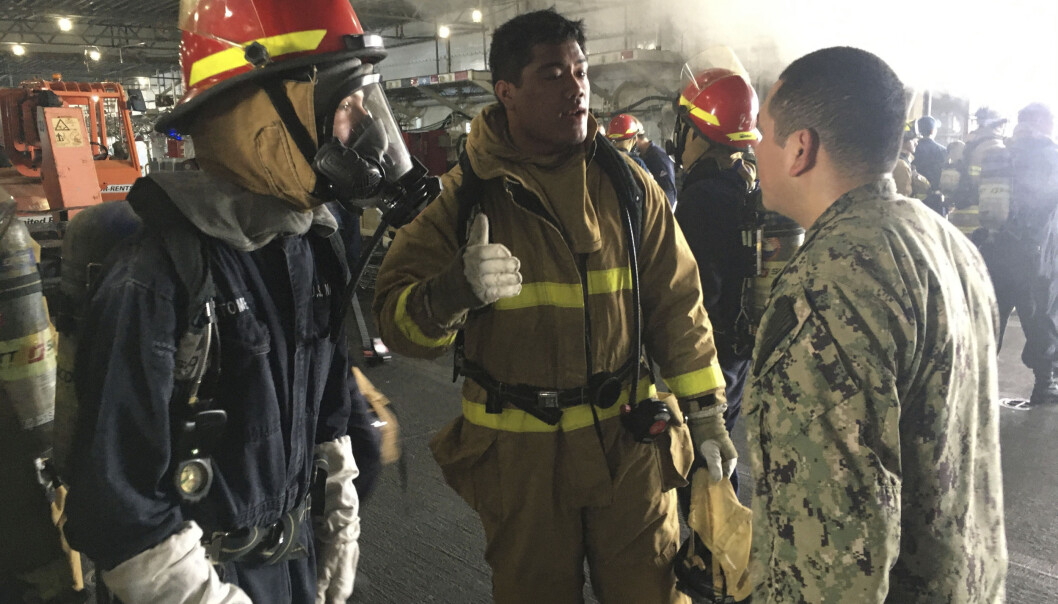 Dette bildet er sendt ut av U.S. Navy og viser brannpersonell og militært personell diskutere brannen. Dette bildet er sendt ut av U.S. Navy og viser brannpersonell og militært personell diskutere brannen.