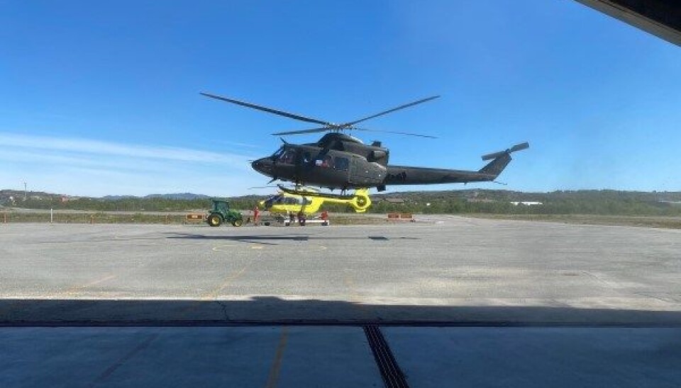 Norsk Luftambulanse AS' helikopter i bakgrunnen og Forsvarets Bell 412-helikopter i forgrunnen.