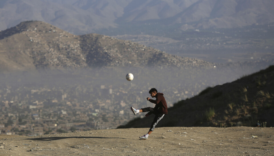 En ung afghansk gutt spiller fotball på en slette i utkanten av hovedstaden Kabul. Bildet er datert 21. juni.