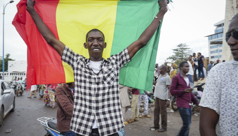 En mann holder opp flagget mens han feirer sammen med andre i gatene i Bamako i Mali. Bildet er datert tirsdag 18. august. En mann holder opp flagget mens han feirer sammen med andre i gatene i Bamako i Mali. Bildet er datert tirsdag 18. august.