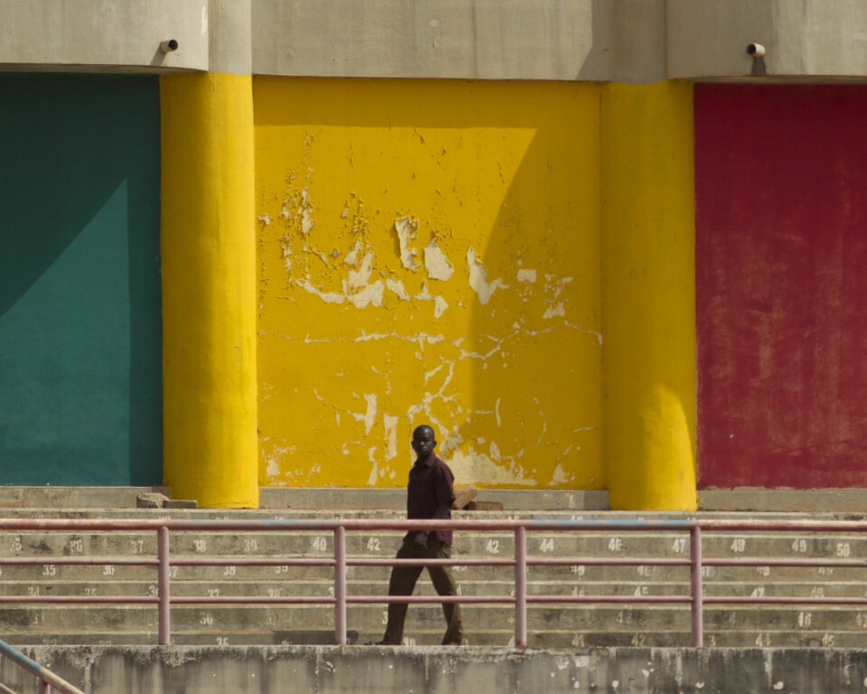 A man walks in front of a wall painted in the colors of the Malian flag, during a rally in support of the ruling military junta attended by roughly one thousand people in a stadium with a capacity of 50,000, in Bamako, Mali Saturday, March 31, 2012. The March 26 stadium is named in commemoration of the date in 1991 when dictator Moussa Traore was overthrown, paving the way for establishment of a democracy which lasted 21 years until mutinous soldiers took power in a coup nine days ago. (AP Photo/Rebecca Blackwell)
