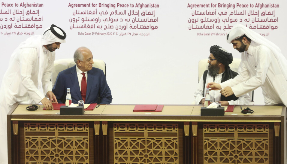 SIGNERER: I dette bildet fra 29. februar 2020, signerer den amerikanske utsendingen Zalmay Khalilzad, (t.v.), og Talibans Mullah Abdul Ghani Baradar en fredsavtale i Doha, Qatar. Det er denne avtalen som skisserte en uttrekning av amerikanske styrker innen 1. mai 2021.