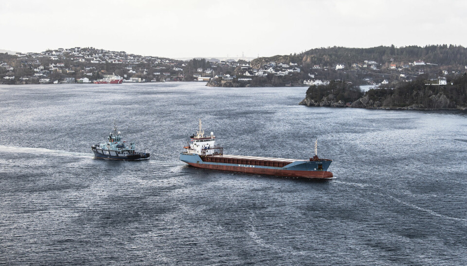 Lasteskipet «Wilson Parnu» som fikk motorstans og havnet i trøbbel sørvest for Sotra kjører nå under Askøybrua på veg mot Bergen. Slepebåten «Vortex» henger på og hjelper til med styringen.
