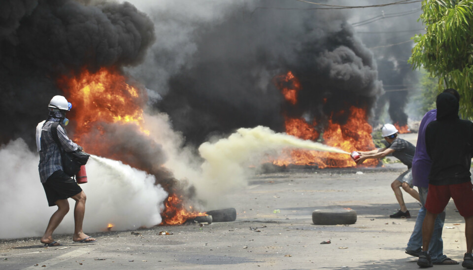 Demonstranter forsøke å slukke branner under en protest i Thaketa Township, søndag.