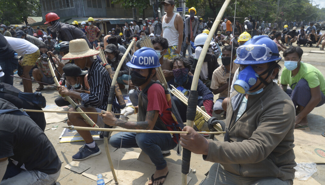 Kuppmotstandere væpnet med pil og bue i en konfrontasjon med politiet i bydelen Thaketa i Myanmar lørdag. Kuppmotstandere væpnet med pil og bue i en konfrontasjon med politiet i bydelen Thaketa i Myanmar lørdag.