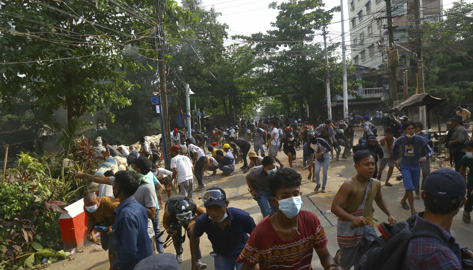 Opprørspoliti bryter opp en folkemengde i Yangon i Myanmar søndag.