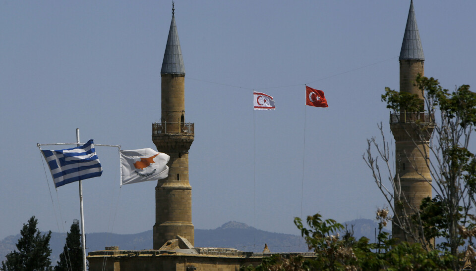 Et gresk og et kypriotisk flagg til venstre og flaggene til Nord-Kypros og Tyrkia til høyre mellom minaretene til Selimiye-moskeen, tidligere St. Sofia-katedralen, ved delingslinjen i Nikosia mellom staten Kypros og Nord-Kypros.