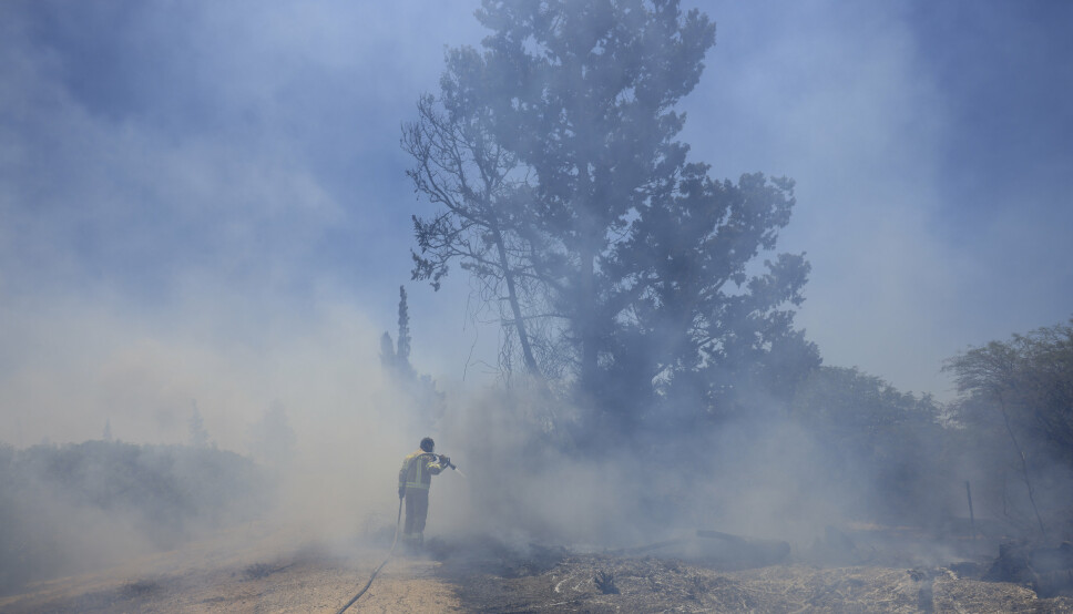 BRANN: En israelsk brannmann forsøker å slukke brannene etter palestinere sendte brannballonger mot grensa mellom Israel og Gaza.