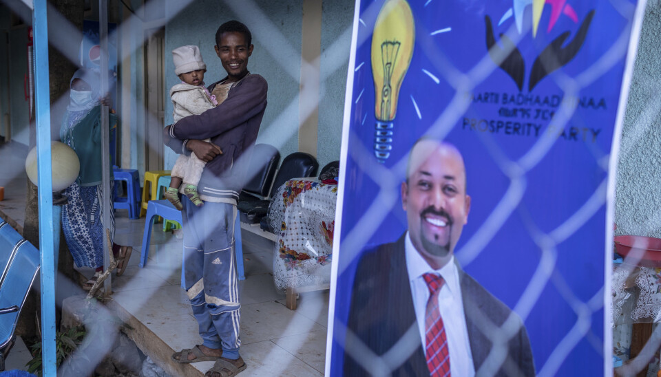 20 år gamle Gezale Abamecha, som har datteren på armen, står ved siden av en valgplakat der Etiopias statsminister Abiy Ahmed ber om fornyet tillit fra velgerne. Mandag holdes det valg på ny nasjonalforsamling i Etiopia, men millioner får ikke delta.
