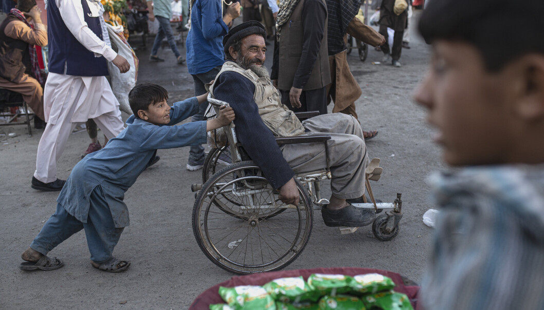 AFGHANISTAN: En gutt dytter en mann i rullestol gjennom et marked i Kabul. AFGHANISTAN: En gutt dytter en mann i rullestol gjennom et marked i Kabul.