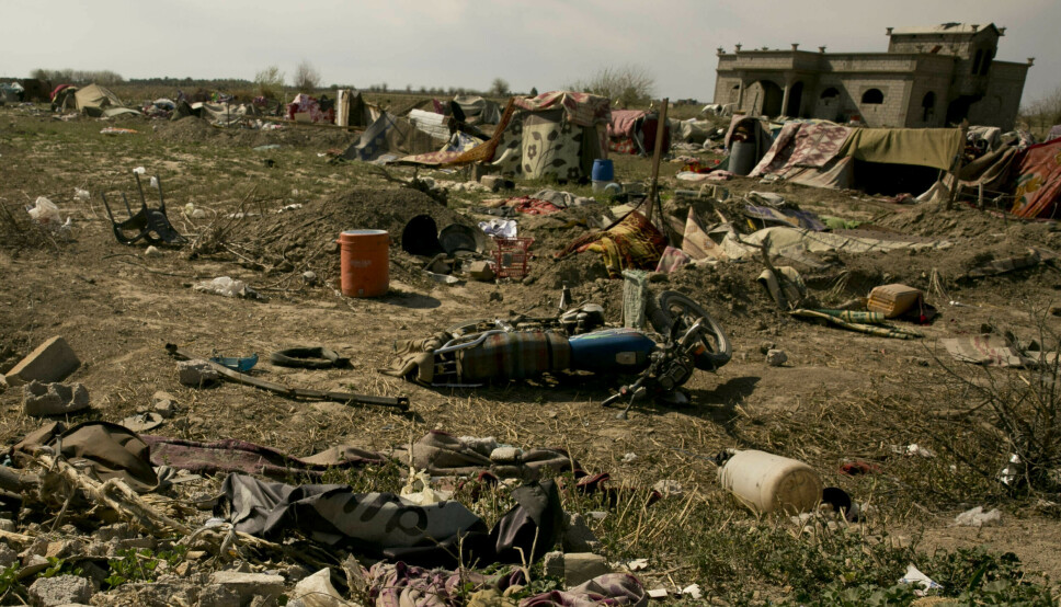 BAGHOUZ: Et IS-flagg ligger krøllet i forgrunnen. Bildet er fra Baghouz etter at USA-støttede syriske styrker tok tilbake kontrollen over byen i mars 2019.