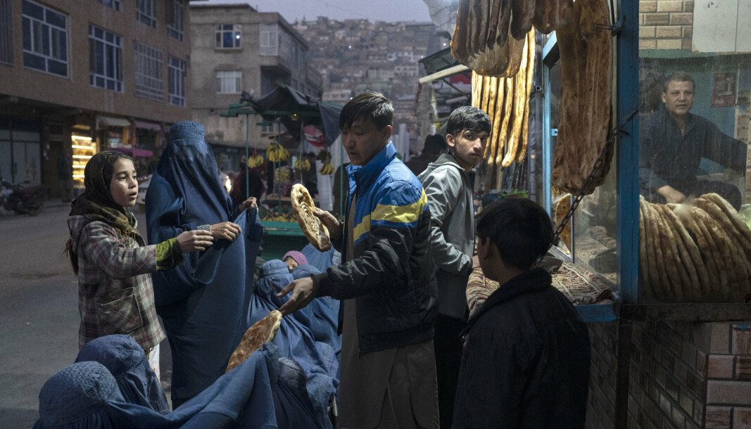 AFGHANISTAN: En mann deler ut brød til afghanske kvinner utenfor et bakeri i Kabul torsdag denne uken. Etter 20 år med vestlig militært nærvær gjenerobret Taliban makten i landet tidligere i år.