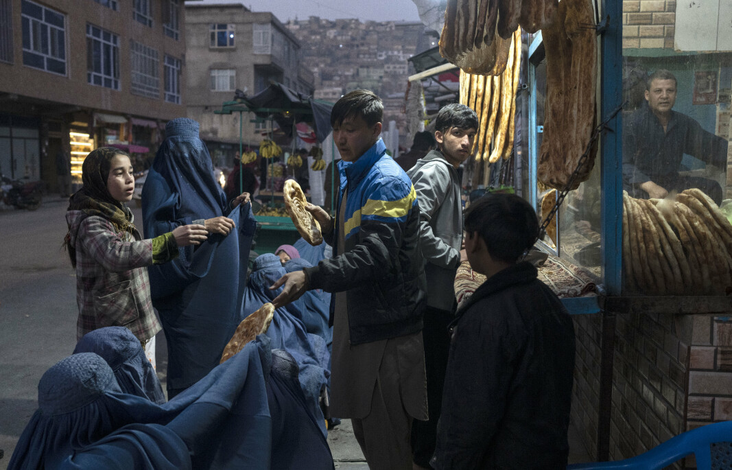 SULT: En mann deler ut brød til Afghanske kvinner og barn. I følge FN lider rundt 60 prosent av folket i landet under akutt hungersnød.