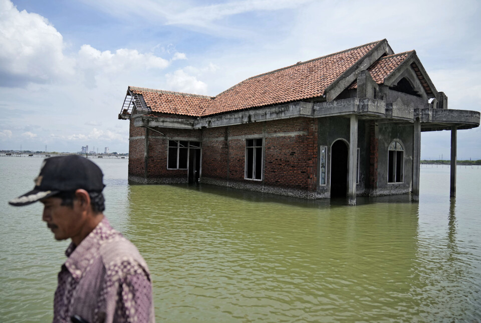 STIGANDE HAVNIVÅ: Ein mann paserer eit hus som er forlatt fordi stigande havnivå har dekt golvet i første etasje. Biletet er frå Sidogemah i Indonesia og er datert 8. november 2021.
