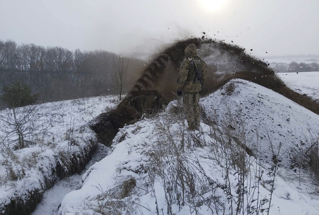 PÅ GRENSEN: Dette arkivbildet er distribuert av den ukrainske grensevakten og viser en vakt som passer på mens et spesialkjøretøy graver en grøft. Bildet er fra Sumy og er datert 21. desember 2021. PÅ GRENSEN: Dette arkivbildet er distribuert av den ukrainske grensevakten og viser en vakt som passer på mens et spesialkjøretøy graver en grøft. Bildet er fra Sumy og er datert 21. desember 2021.