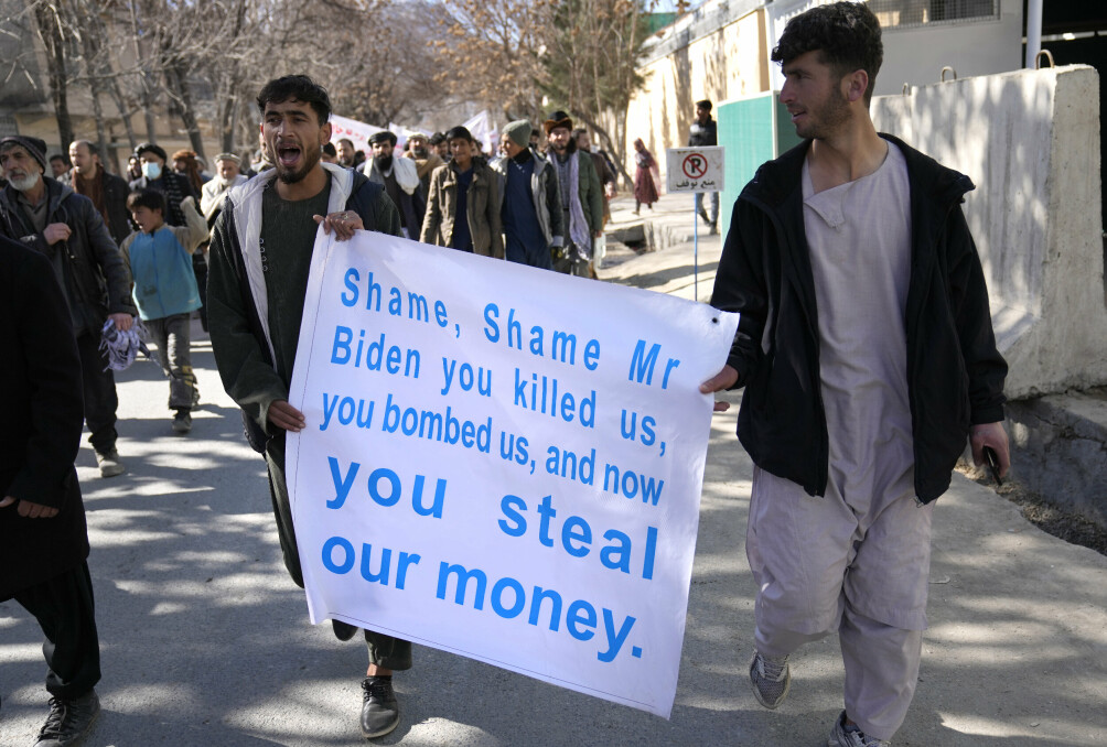 Afghan protesters hold a placard, as they shout anti-U.S. slogans during a protest condemning President Joe Biden's decision, in Kabul, Afghanistan, Tuesday, Feb. 15, 2022. President Biden signed an executive order, on Feb. 11, to create a pathway to split $7 billion in Afghan assets frozen in the U.S. to fund humanitarian relief in Afghanistan and to create a trust fund to compensate Sept. 11 victims. (AP Photo/Hussein Malla)