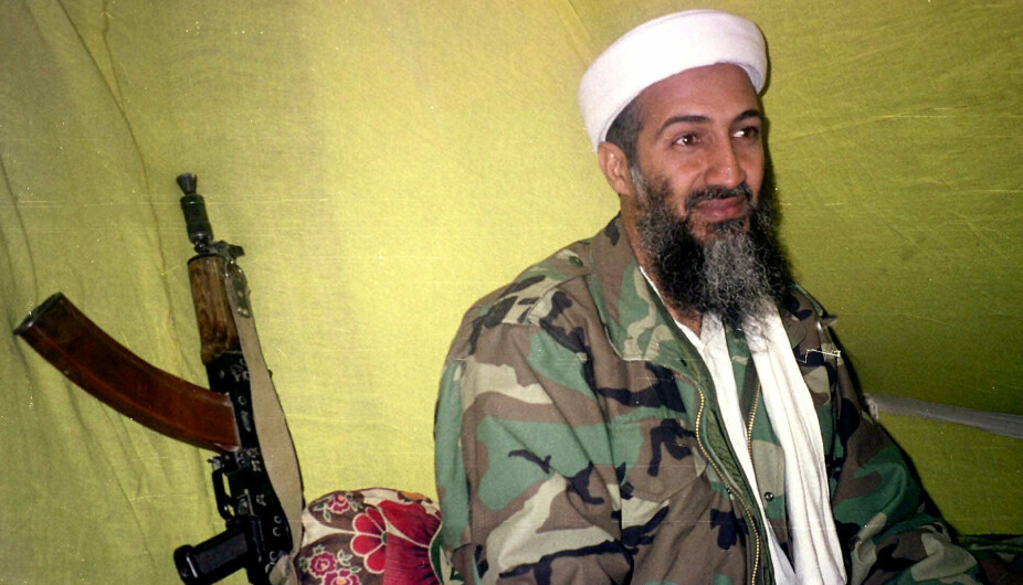 FILE - In this Dec. 24, 1998, file photo, al-Qaida leader Osama Bin Laden speaks to a selected group of reporters in mountains of Helmand province in southern Afghanistan. When the reclusive Islamic State group leader Abu Bakr al-Baghdadi  appeared in a video Monday, he was the latest in a series of most-wanted figures, to use the medium to communicate with the outside world. Al-Baghdadi in his latest video mirrored a picture of Osama Bin Laden in his videos, sitting cross-legged with an assault rifle kept against the wall next to him. (AP Photo/Rahimullah Yousafzai, File)