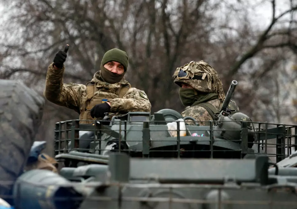 FÅR STØTTE: En ukrainsk soldat gir tommel opp mens han kjører forbi i et militært kjøretøy, på vei til kamp i Lugansk fylke lørdag. Russland beordret samme dag sine styrker om å rykke frem i Ukraina fra alle retninger.