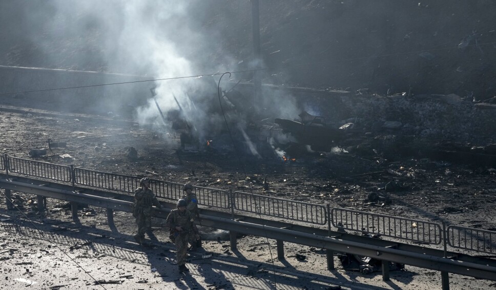 UTBRENT: Ukrainske soldater går på gata i Kyiv mellom deler av brente militære kjøretøy den 26. februar 2022.
