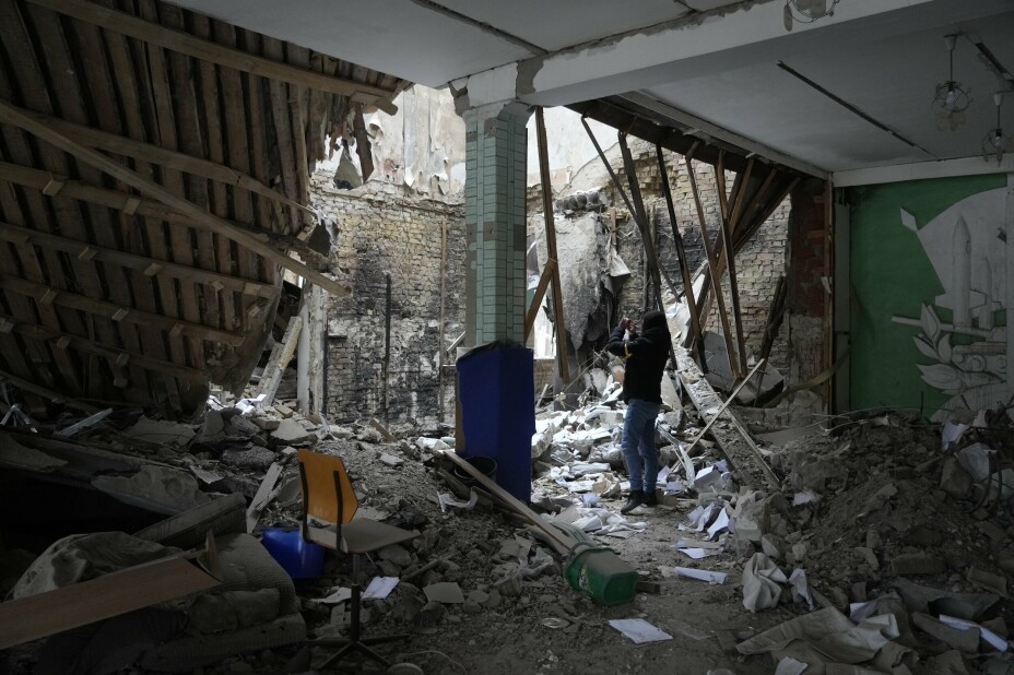 En kvinne tar bilde at en ødelagt bygning i Brovary litt utenfor Kyiv.