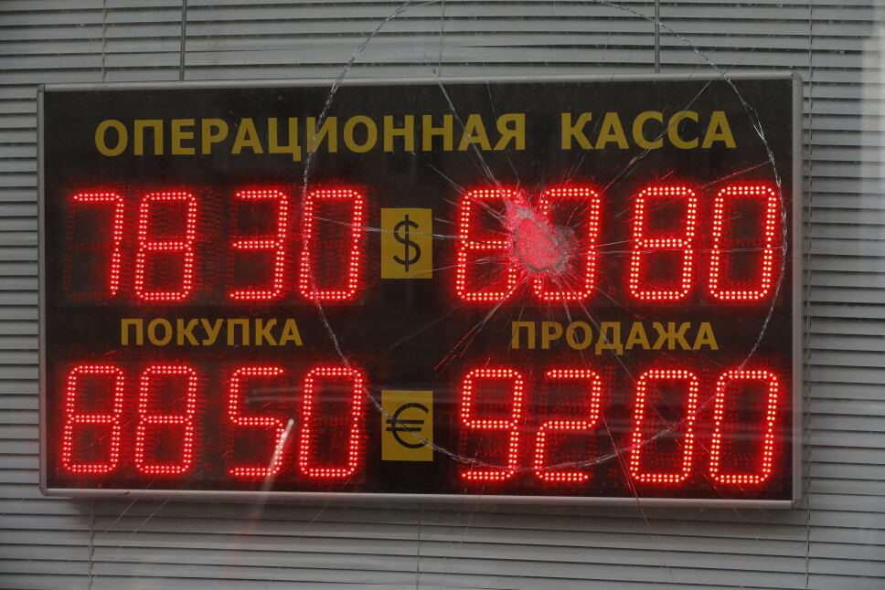 En skjerm er sett gjennom et skadet glass viser valutakursene til U.S. Dollar og euro til russiske rubler i Moskva, Russland, tirsdag 22. februar.