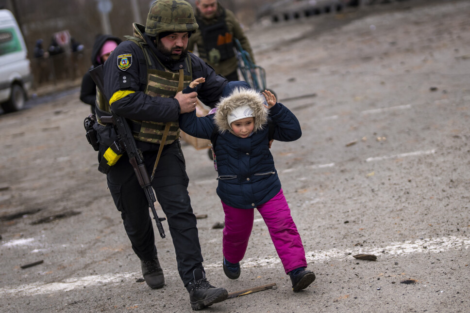 FLYKTNINGER: En ukrainsk politimann hjelper en liten jente til å flykte fra Kyiv-forstaden Irpin.
