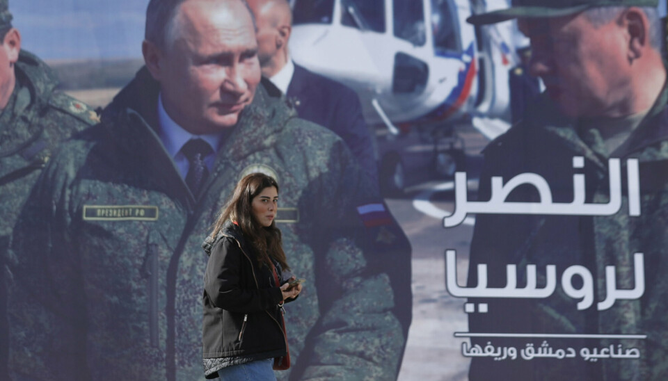 RUSSLAND-STØTTE: I Syria støtter regjeringen til Bashar al-Assad Russlands krig mot Ukraina. Her går en kvinne forbi en reklametavle satt opp i Damaskus. På bildet av Russlands president Vladimir Putin står det «Seier for Russland» på arabisk.