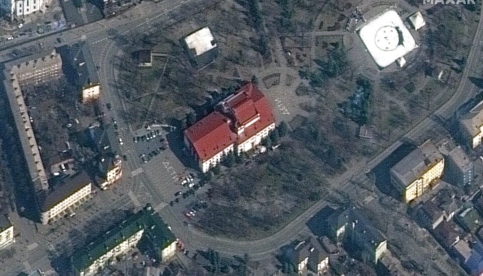 BARN: Dette satellittbilder fra Maxar Technologies skal vise teateret i Mariupol og er datert 14. mars. Maxar opplyser at de hvite bokstavene i hvitt foran og bak bygningen er skrevet på russisk og betyr 'barn'.