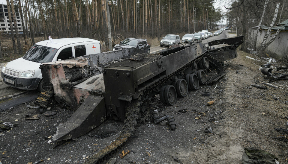 EVAKUERING: En kolonne med biler med folk som evakueres fra Irpin ved Kyiv, passerer en ødelagt russisk stridsvogn.