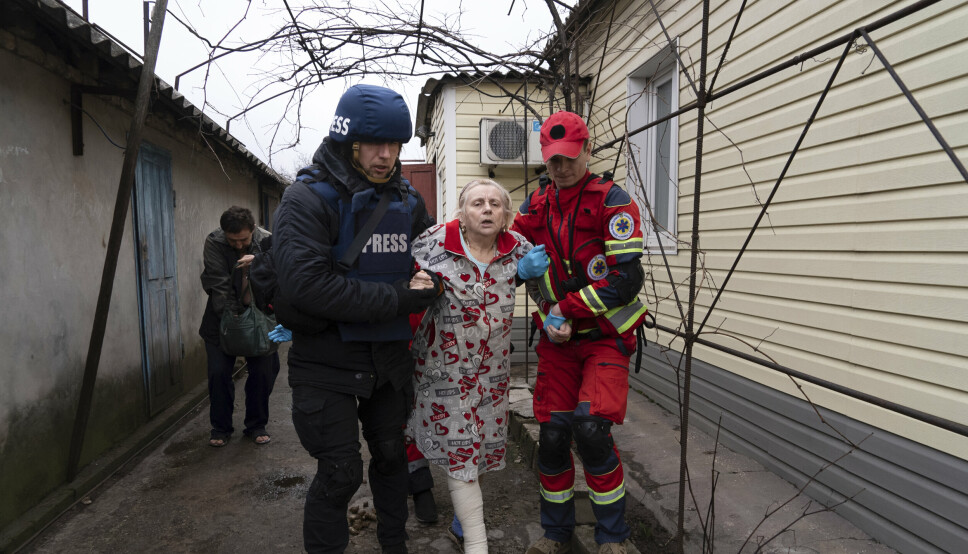 BOMBARDEMENT: AP-fotograf Evgeniy Maloletka hjelper til med å bringe en såret kvinne bort under et granatangrep i Mariupol. Ukranias president Volodymyr Zelenskyj har sammenliknet angrepene på Mariupol med beleiringen av Leningrad.