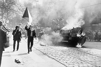 Under den sovjetiske invasjonen av Tsjekkoslovakia bærer tsjekkoslovakene sitt nasjonalflagg forbi en brennende stridsvogn i Praha.