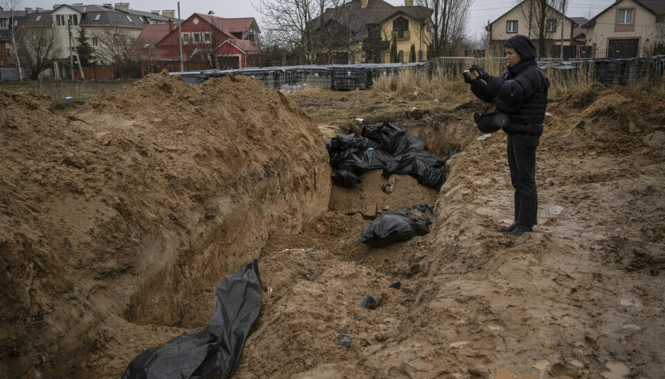 GRAV: Russland hevder at bildene av døde fra en massegrav i Butsja utenfor Kyiv ikke er ekte og er arrangert av ukrainske myndigheter. Her tar en journalist bilde av massegraven.