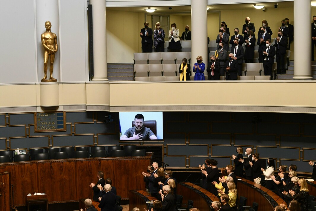 DISKUSJON: Finske folkevalgte lytter til Ukrainas president Volodymyr Zelenskyj som holdt en videotale i parlamentet i Helsingfors fredag. Dagen etter åpnet regjeringspartiet Centern for Nato-medlemskap.