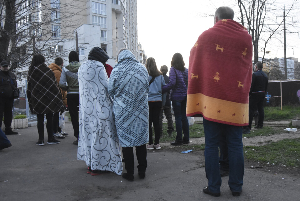 ODESA: Beboere står dekket av tepper ved siden av husene sine som er skadet av russisk bombing i Odesa, Ukraina, lørdag 23. april.