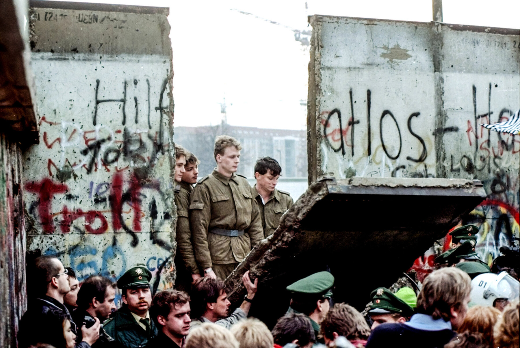 ADVANCE FOR SUNDAY, NOV. 7 --FILE -- East German border guards look through a hole in the Berlin Wall after demonstrators pulled down the segment at Brandenburg Gate in Berlin, in this Nov. 11, 1989 file photo. Ten years after the fall of the Wall, Germany continues to struggle with the culture shock of reunification. (AP Photo/FILE/Lionel Cironneau) ADVANCE FOR SUNDAY, NOV. 7 --FILE -- East German border guards look through a hole in the Berlin Wall after demonstrators pulled down the segment at Brandenburg Gate in Berlin, in this Nov. 11, 1989 file photo. Ten years after the fall of the Wall, Germany continues to struggle with the culture shock of reunification. (AP Photo/FILE/Lionel Cironneau)