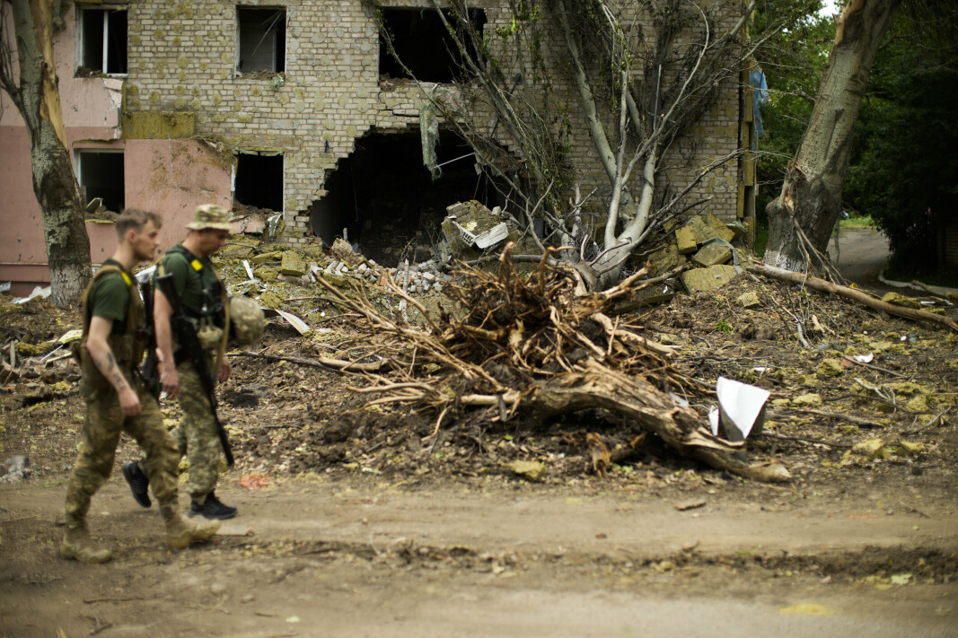 SOLDATER: Ukrainske soldater går forbi en bygning som ble kraftig rammet av russiske angrep i Bakhmut øst i Ukraina, samtidig som flere kamper kjempes i nabobyene Lysytsjansk og Sievjerodonetsk. Bildet er tatt 28. mai.