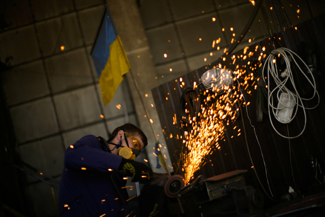 LAGER MATERIALE: En ukrainsk innbygger former metallplater med en vinkelsliper ved et anlegg som produserer materiale for ukrainske soldater i Zaporizjzja, Ukraina. Bildet ble tatt 7.mai 2022.