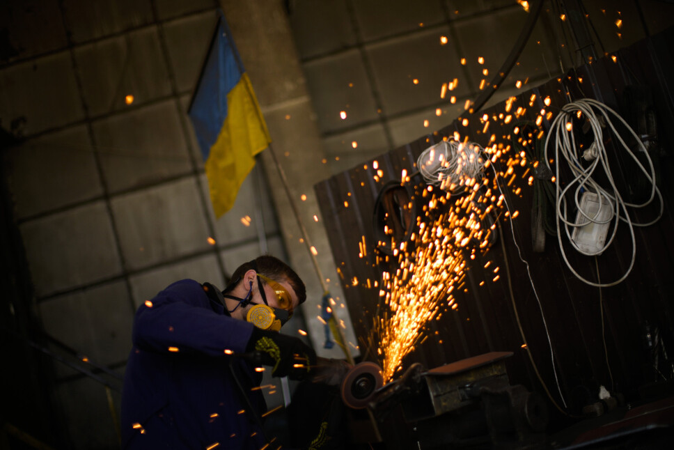 LAGER MATERIALE: En ukrainsk innbygger former metallplater med en vinkelsliper ved et anlegg som produserer materiale for ukrainske soldater i Zaporizjzja, Ukraina. Bildet ble tatt 7.mai 2022.