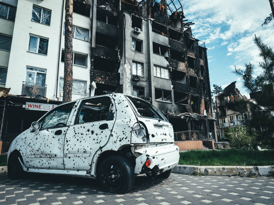 BILVINDUENE ER BLÅST UT: Bilen som står parkert ved noen bygninger i Butsja har fått store skader etter kampen mellom russiske og ukrainske styrker. Foto: Morten Risberg