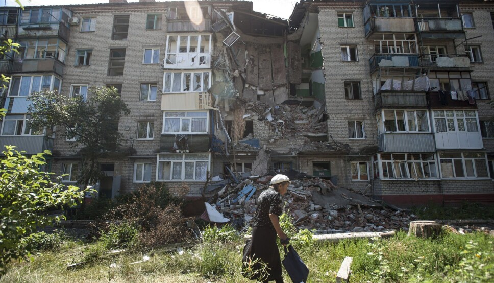 SKADET: En kvinne går forbi en bygning som er skadet av granater i Slavjansk, øst i Ukraina.