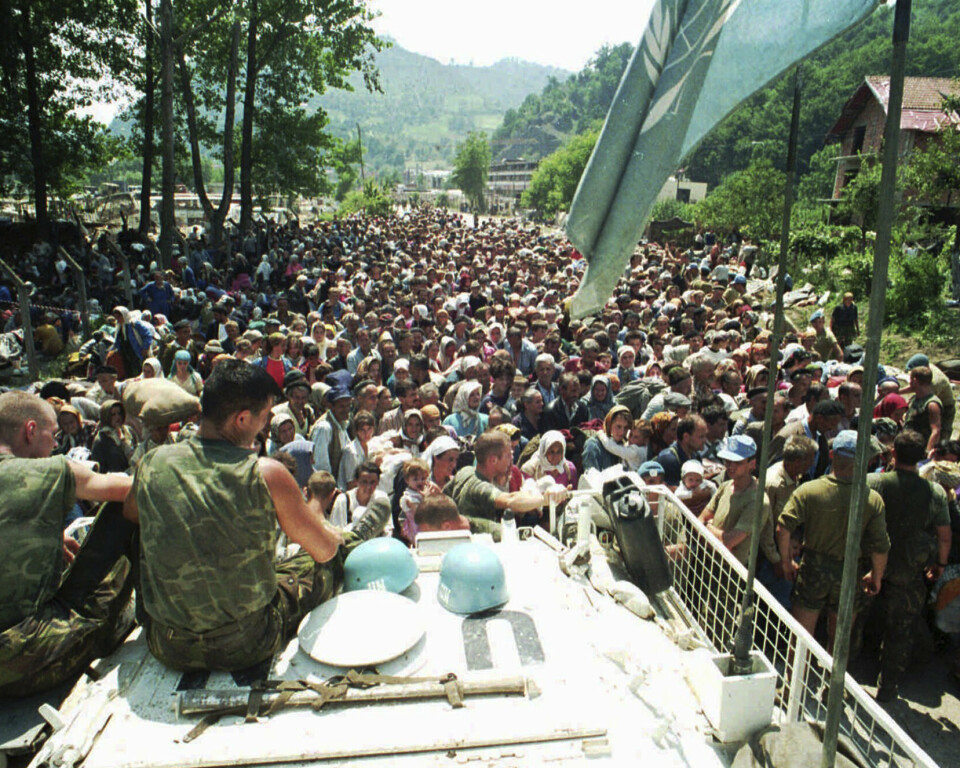 FILE - In this July 13, 1995 file photo, Dutch U.N. peacekeepers sit on top of an armored personnel carrier while Muslim refugees from Srebrenica, eastern Bosnia, gather in the village of Potocari, just north of Srebrenica. The Dutch defense minister announced Wednesday Feb. 10, 2021, that the government will pay veterans of a United Nations peacekeeping mission that failed to prevent the massacre of thousands of Bosnian Muslims by Bosnian Serbs in 1995 5,000 euros each as a 'gesture and token of appreciation' for their service in horrific circumstances. (AP Photo/File)
