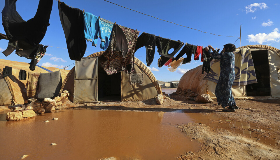HJELPETRENGENDE: En kvinne henger opp klesvasken ved en flyktningleir i Idlib, Syria.