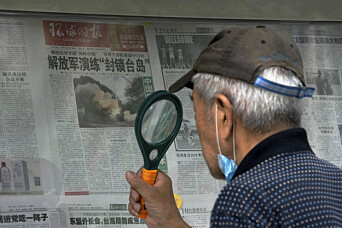 ØVELSE: En mann i Beijing bruker forstørrelsesglass til å lese en avis med nyheter om de omfattende militærøvelsene Kina satte i gang etter Nancy Pelosis besøk på Taiwan.