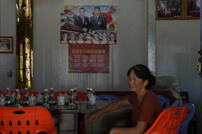 POLITIKK: En kvinne sitter foran en plakat med bilder av Kinas president Xi Jinping og statsminister Li Keqiang i Pingtan i Fujian-provinsen.