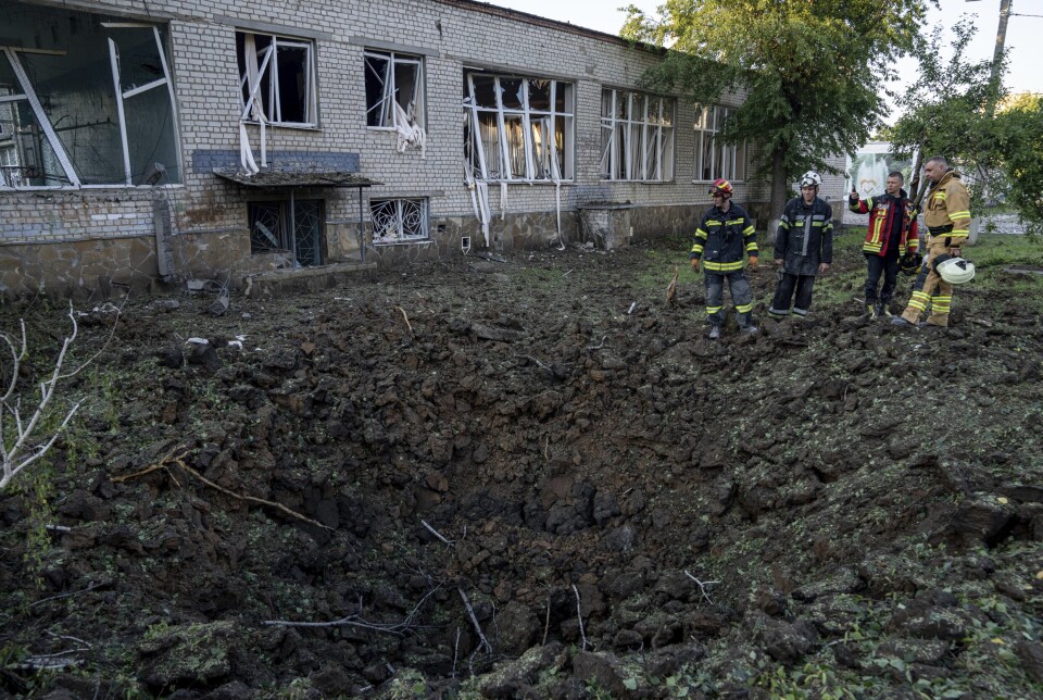 ANGREP: Ukrainske redningsmenn ser på et krater i en skolegård etter et angrep i Kharkiv, Ukraina, mandag 4. juli 2022. Det ukrainske militærets generalstab sier at russiske styrker prøver å presse offensiven sin dypere inn i Øst-Ukraina etter å ha erobret en sentral høyborg .