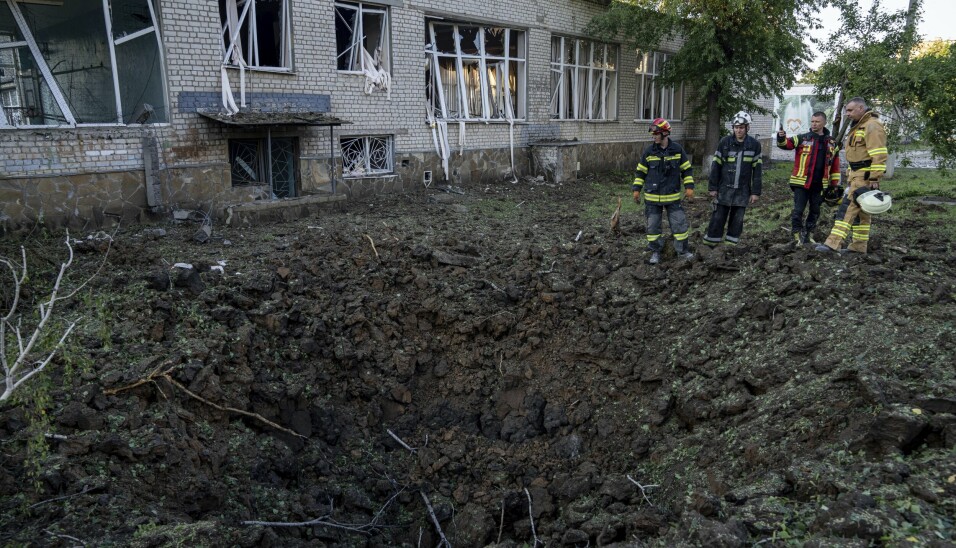 KRATER: Ukrainske redningsmenn ser på et krater i en skolegård etter russernes angrep i Kharkiv 4. juli 2022.