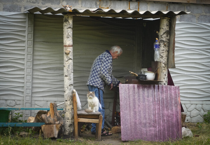 MANGEL PÅ STRØM: En lokal mann fra Luhansk-regionen lager mat utenfor huset sitt, etter tre måneder med mangel på vann og elektrisitet, på grunn av krigen. Bildet ble tatt 16.juni 2022.