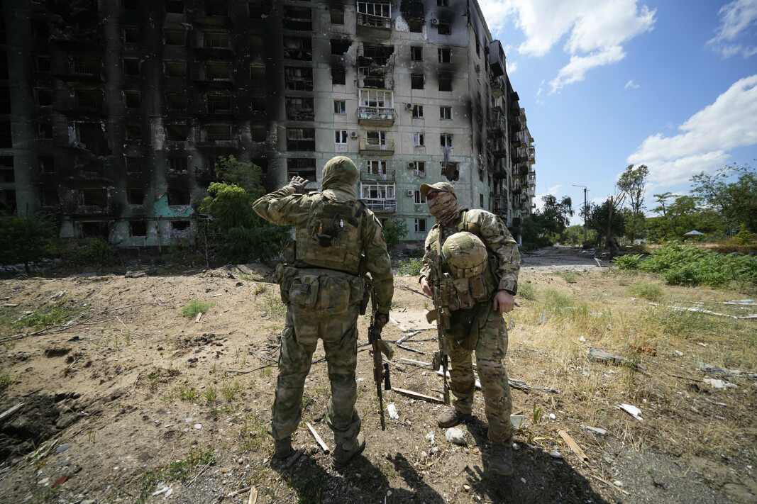SKADER PÅ BYGNING: Russiske soldater står ved en bygning som har fått store skader etter kamper mellom russiske og ukrainske styrker i byen Severodonetsk, som ligger sørøst i Ukraina. Bildet ble tatt 12.juli 2022.