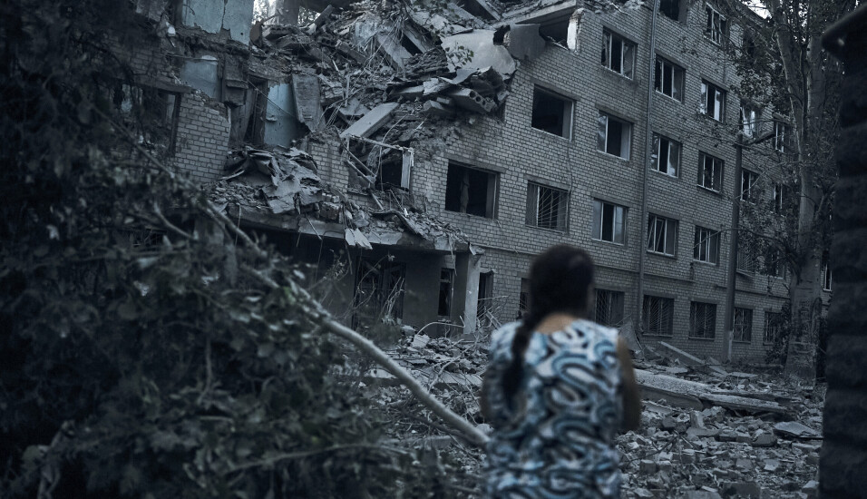 ØDELEGGELSER: En ukrainsk kvinne ser på en boligblokk, etter nattens harde kamper i havnebyen Mykolajiv i Ukraina den 2. august 2022.